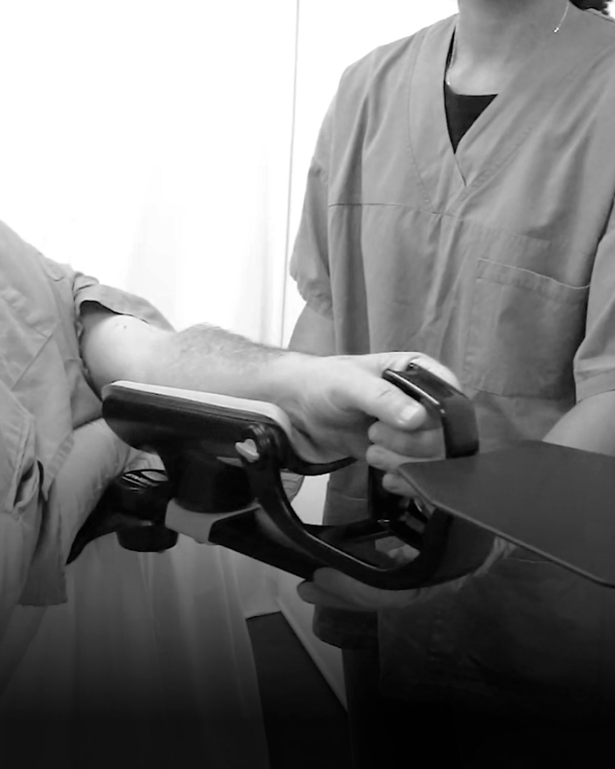 Healthcare worker operating a medical device on a patient's arm.