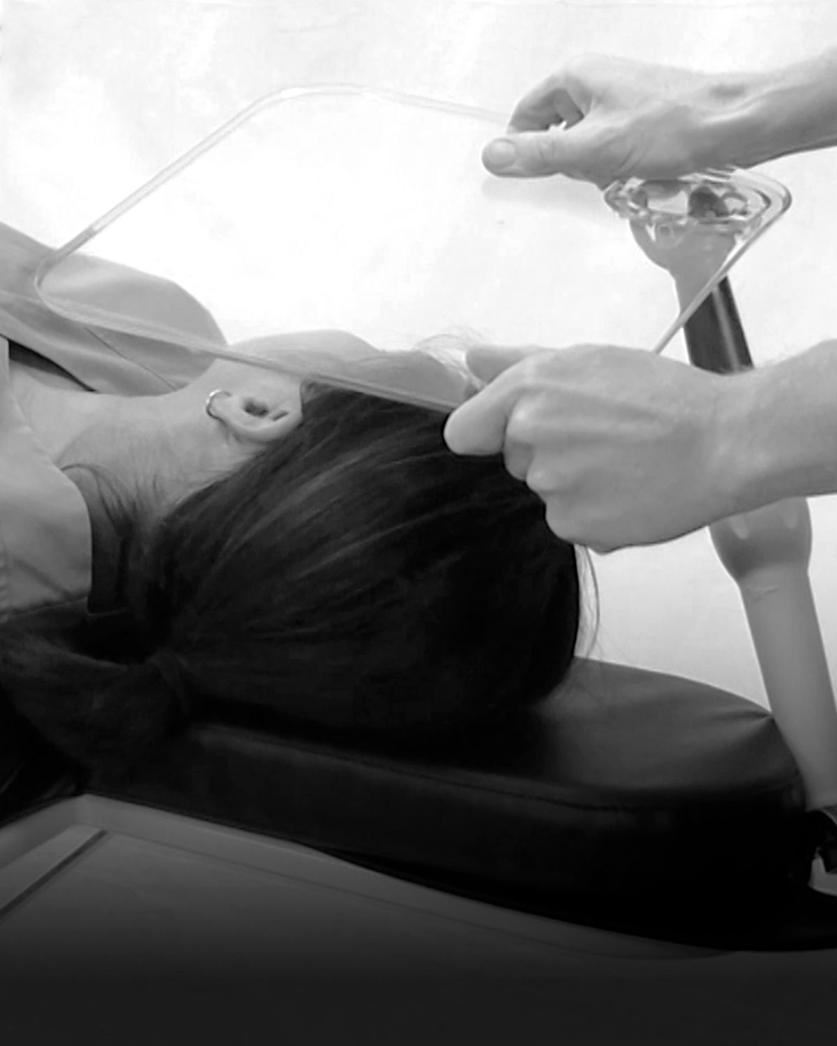 Patient in a dental chair with hands holding an oral suction device.